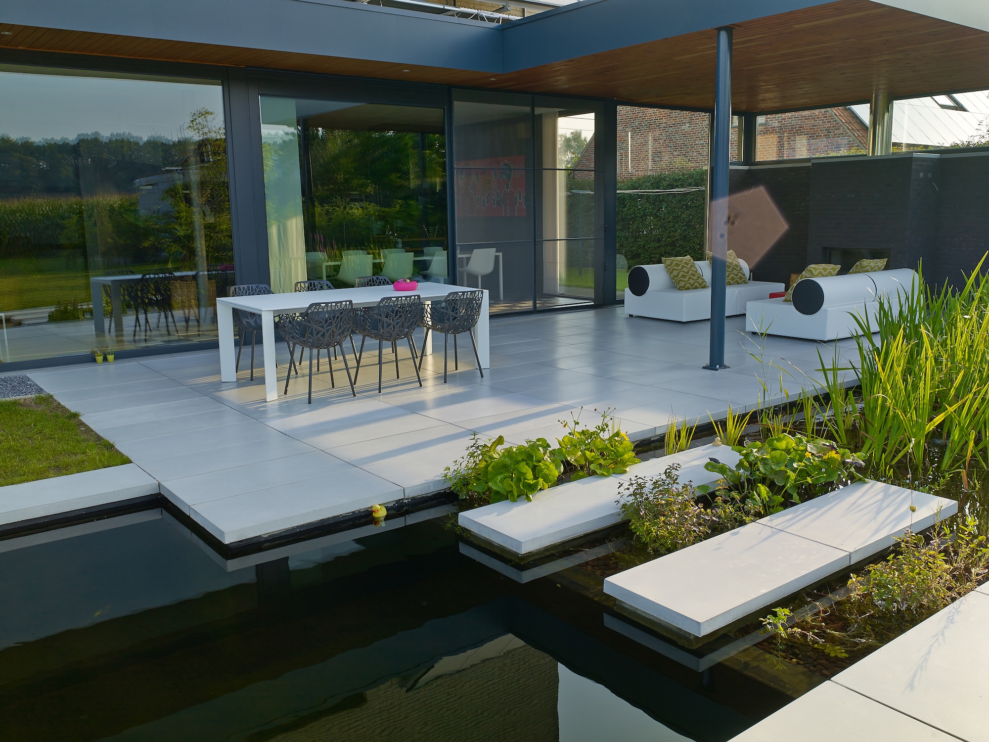 Moderne villa met zwemvijver en witte terrastegels boven het water